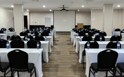 Conference room with black cushioned chairs, table with white covers and white board with projector